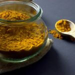 Bicchiere d'acqua con curcuma e limone su un tavolo, simbolo di benessere e salute.