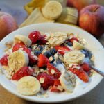Piatto di colazione con avena, frutta fresca e noci per abbassare il colesterolo.