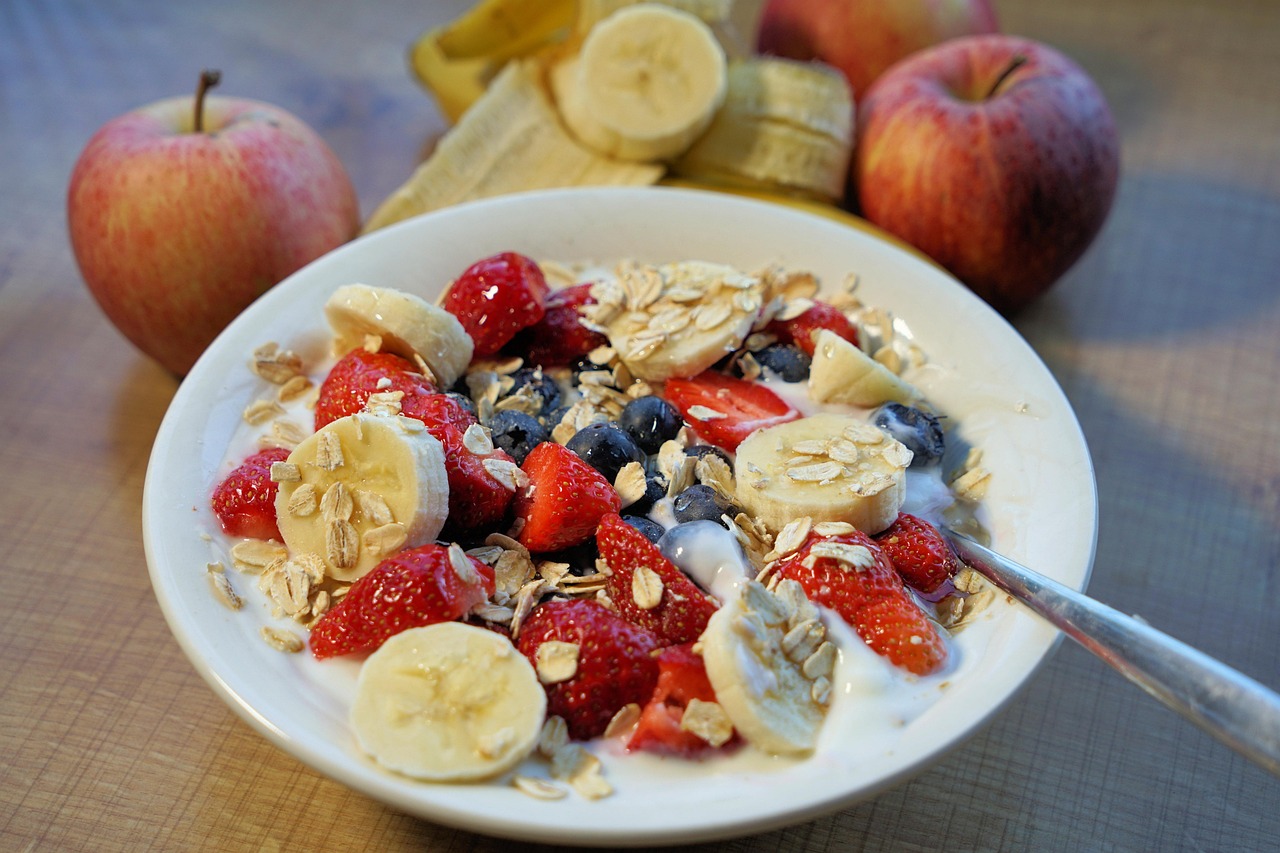 Piatto di colazione con avena, frutta fresca e noci per abbassare il colesterolo.