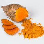 Immagine di curcuma in polvere con cucchiaino, simbolo di salute e benessere per glicemia e colesterolo.