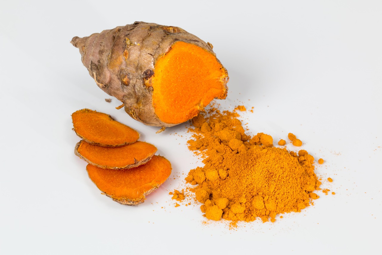 Immagine di curcuma in polvere con cucchiaino, simbolo di salute e benessere per glicemia e colesterolo.