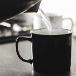 Donna che beve acqua calda, migliorando la digestione secondo studi recenti.