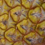 Due fette di ananas fresche su un tagliere, pronte per essere congelate.