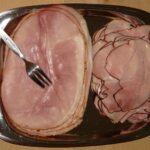 Immagine di un prosciutto cotto con etichetta evidenziata, simbolo di alimentazione poco salutare.