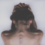 Donna stanca che tiene una mano sulla gola, simboleggiando problemi alla tiroide.