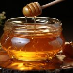 Un barattolo di miele con un cucchiaino, su un tavolo con toast e frutta fresca.