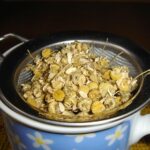 Tazza di camomilla fumante su un tavolo, simbolo di relax e benefici per la salute.